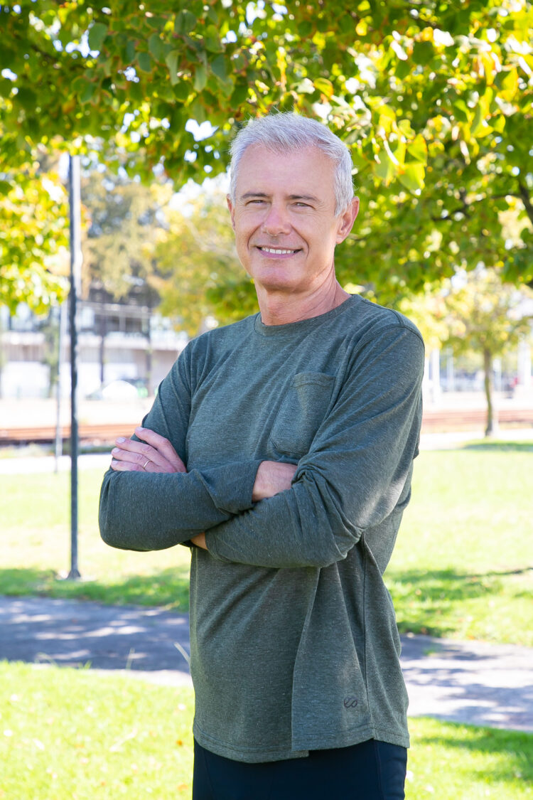 Positive mature man with crossed arms standing outside